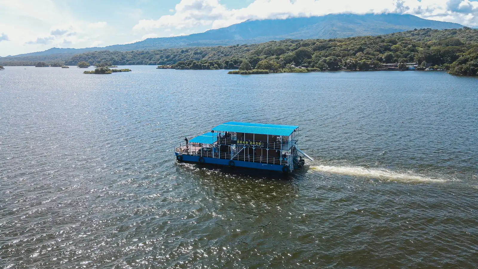 Tour boat crossing Lake Nicaragua near the Isletas de Granada, with Mombacho Volcano behind