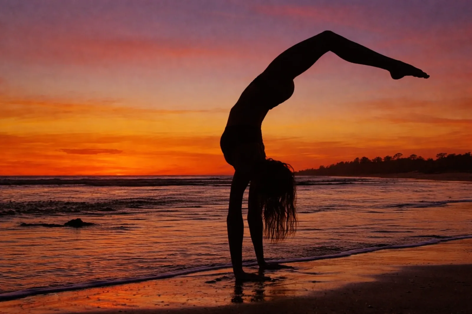 Woman in a yoga backbend on the beach at sunset in Popoyo, Nicaragua